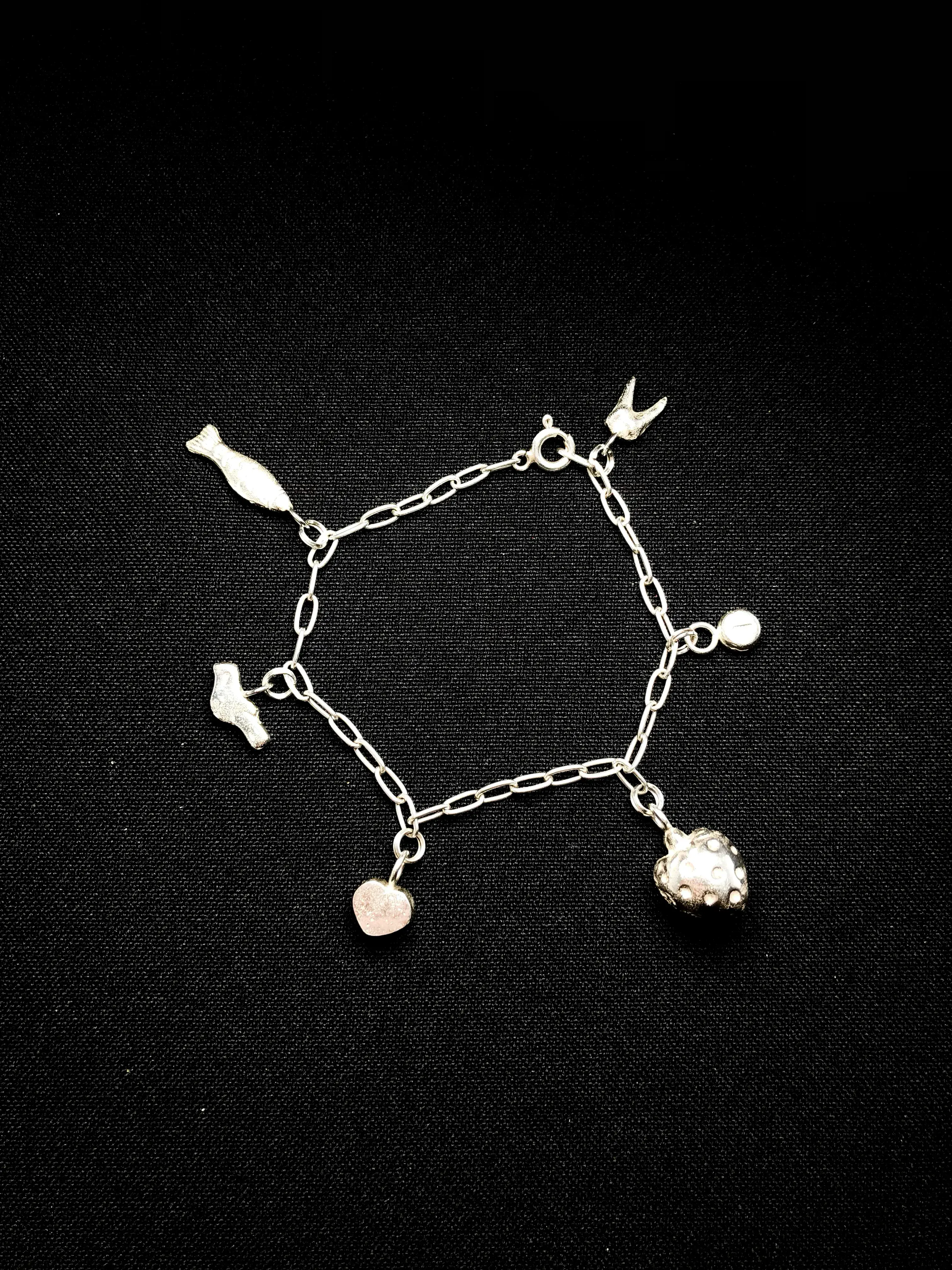 Silver charm bracelet with Until Found charms attached